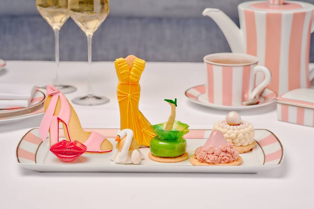 Fashion-themed pastries inspired by red carpet looks, served with champagne and tea on pink-striped china at The Maybourne Beverly Hills